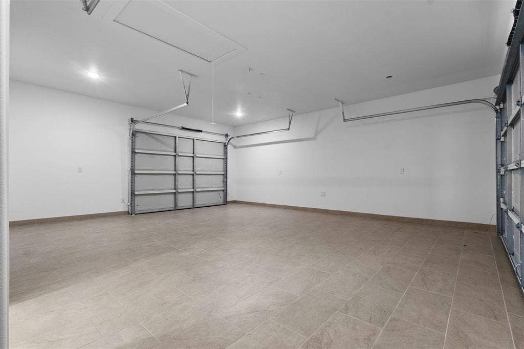 Spacious garage featuring tiled flooring, recessed lighting, and two overhead doors with tracks