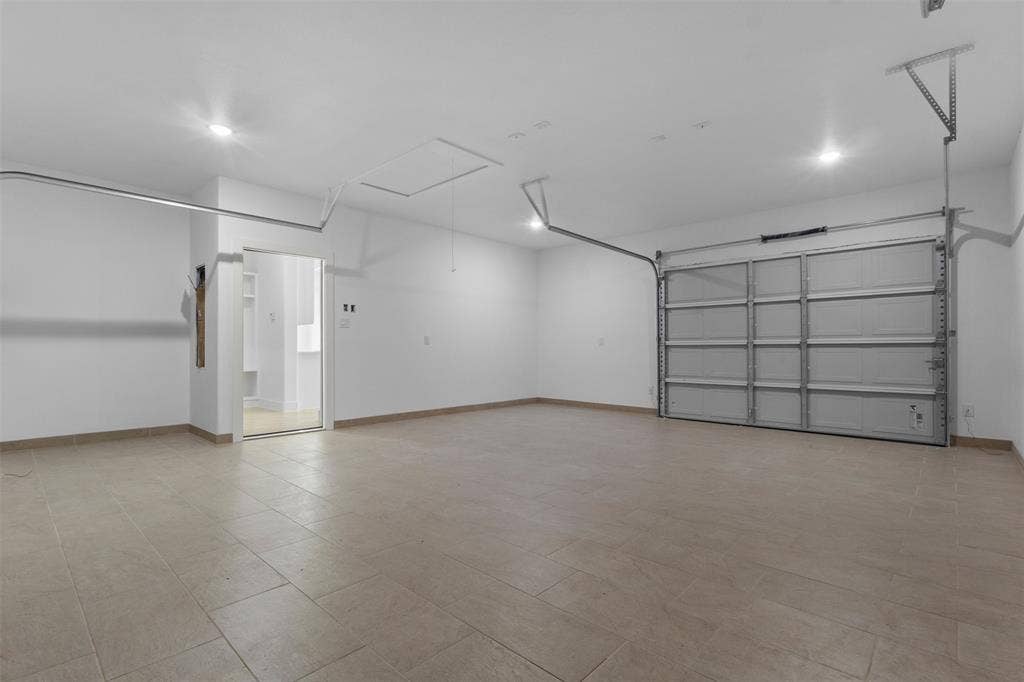 Spacious garage with tile flooring, recessed lighting, and a roll-up garage door
