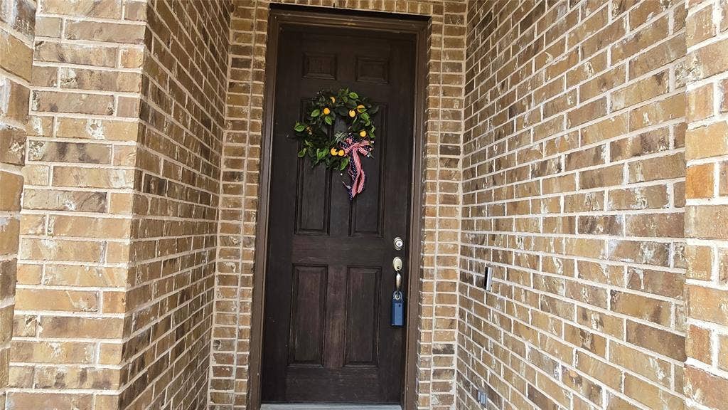 Dark-stained wood entry door featuring a six-panel design and recessed arched top, set within a recessed entryway framed by structural brick masonry