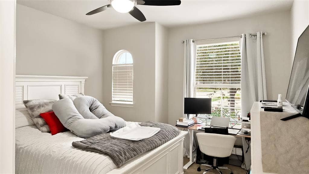 Room featuring an arched window, a multi-blade ceiling fan with integrated lighting, and neutral wall tones