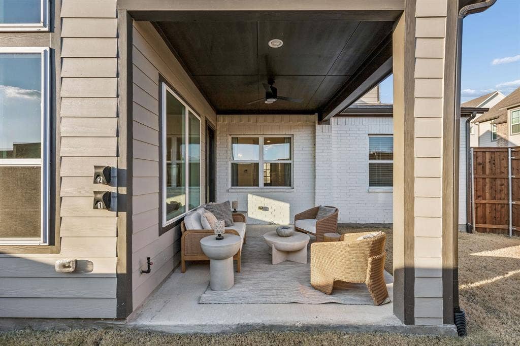 Covered patio featuring a ceiling fan, white brick exterior, siding exterior, and concrete flooring