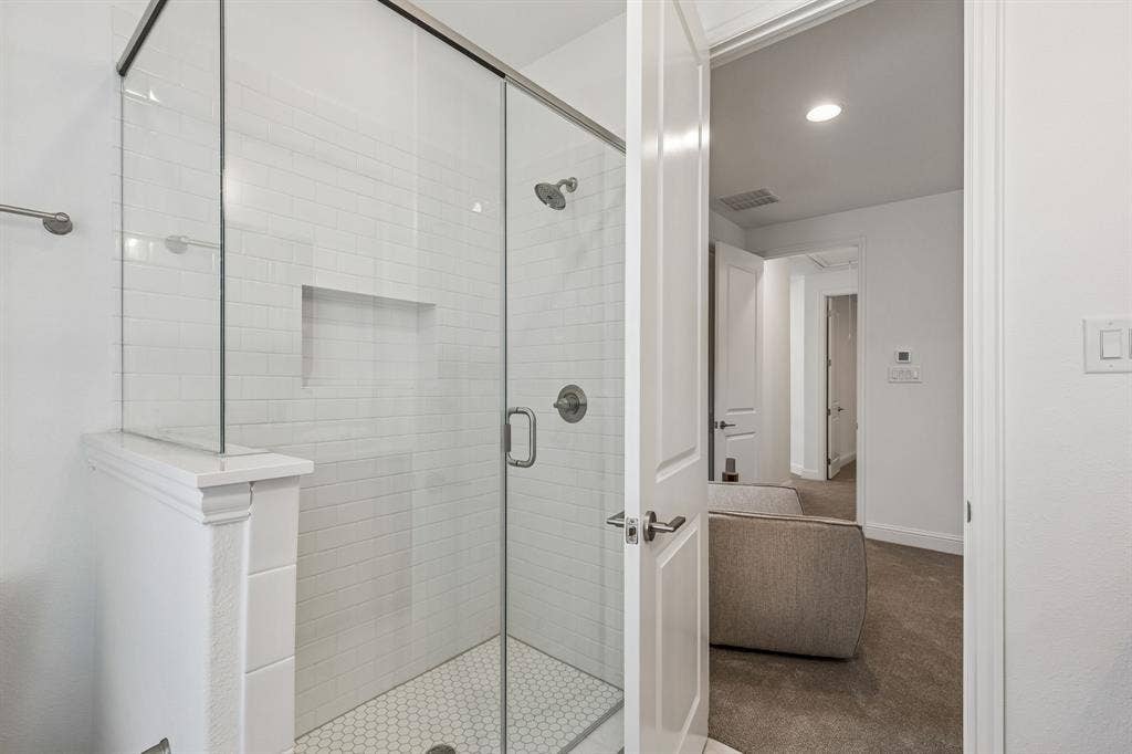 Glass-enclosed shower with subway tile surround, integrated shower niche, and hexagonal tile flooring
