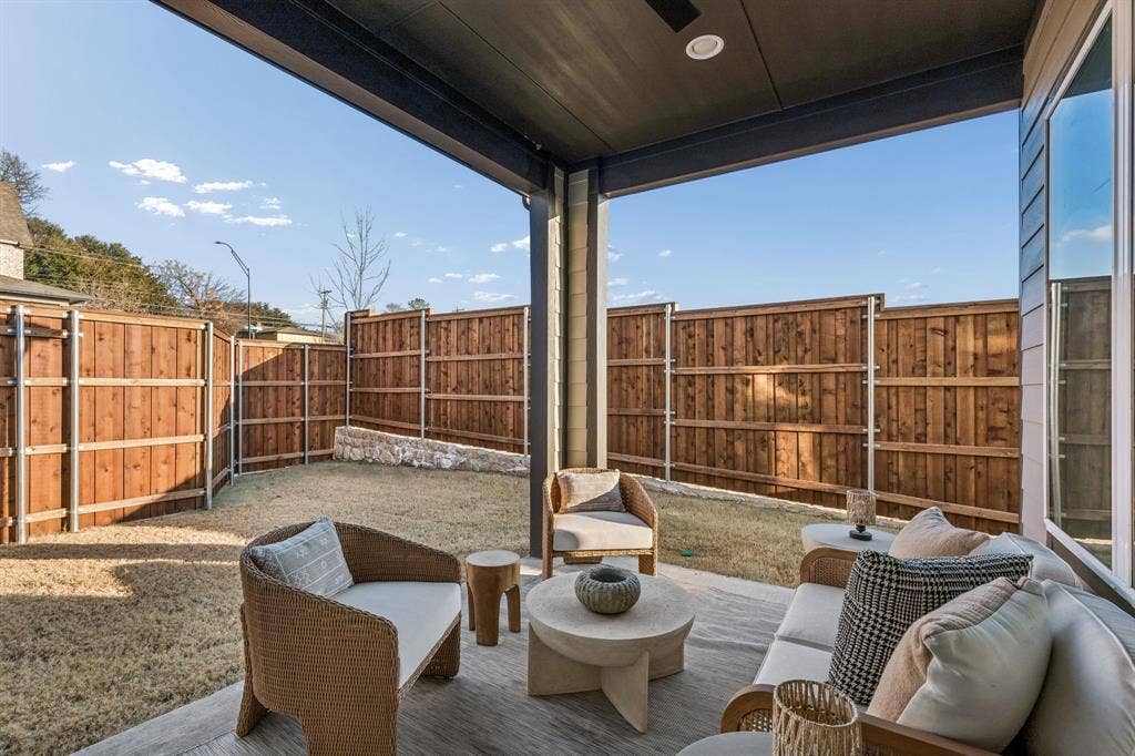 Covered outdoor patio with concrete flooring, recessed lighting, and a dark wood privacy fence