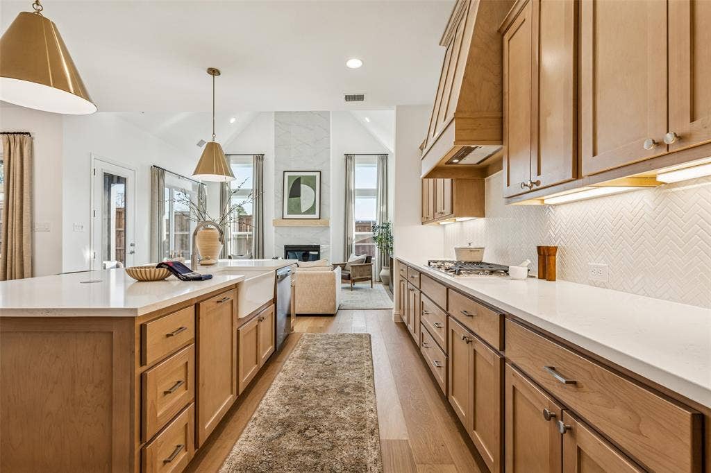 Kitchen featuring light wood cabinetry, white countertops, a herringbone tile backsplash, and wood-finish flooring