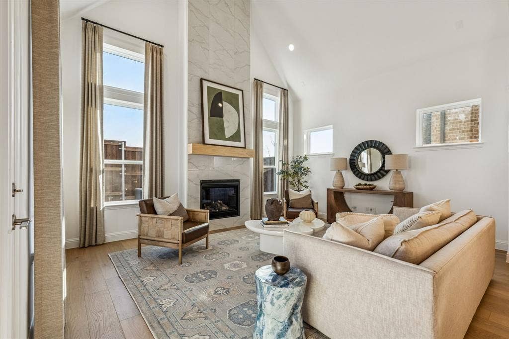 Vaulted ceiling with recessed lighting, wood-finish flooring, a contemporary fireplace with a stone surround, and large windows