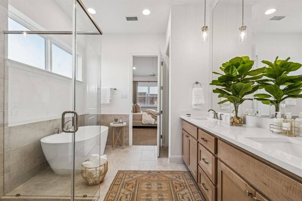 Freestanding soaking tub, glass-enclosed shower, dual vanity with undermount sinks, and wood-finish cabinetry