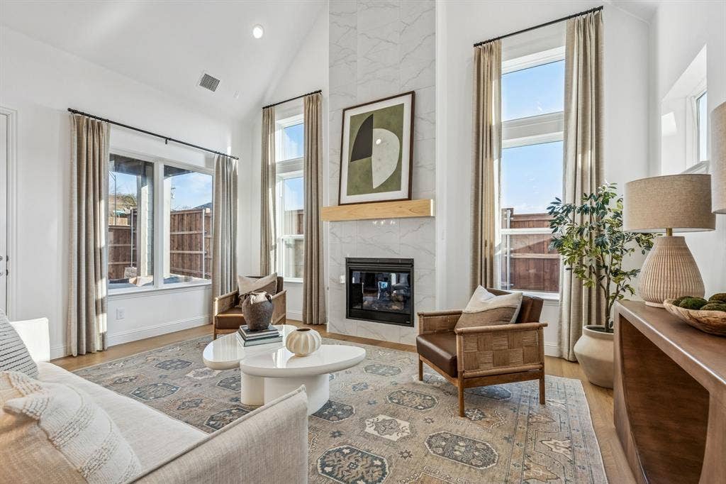 Vaulted ceiling with recessed lighting, large windows, wood-finish flooring, tiled fireplace with a wood mantle, and a built-in fireplace insert