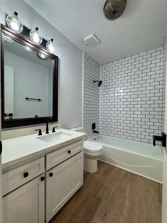 White subway tile shower surround, wood-finish flooring, white vanity with integrated sink, dark bronze hardware, and a framed mirror