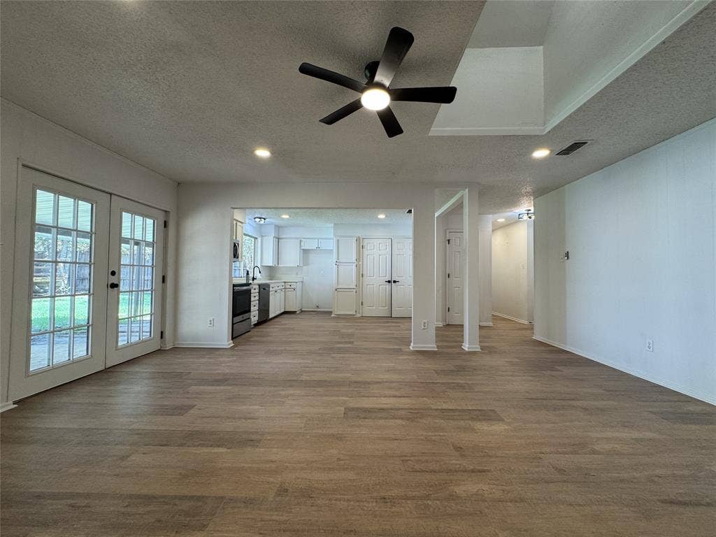Spacious room featuring wood-finish flooring, recessed lighting, and a ceiling fan