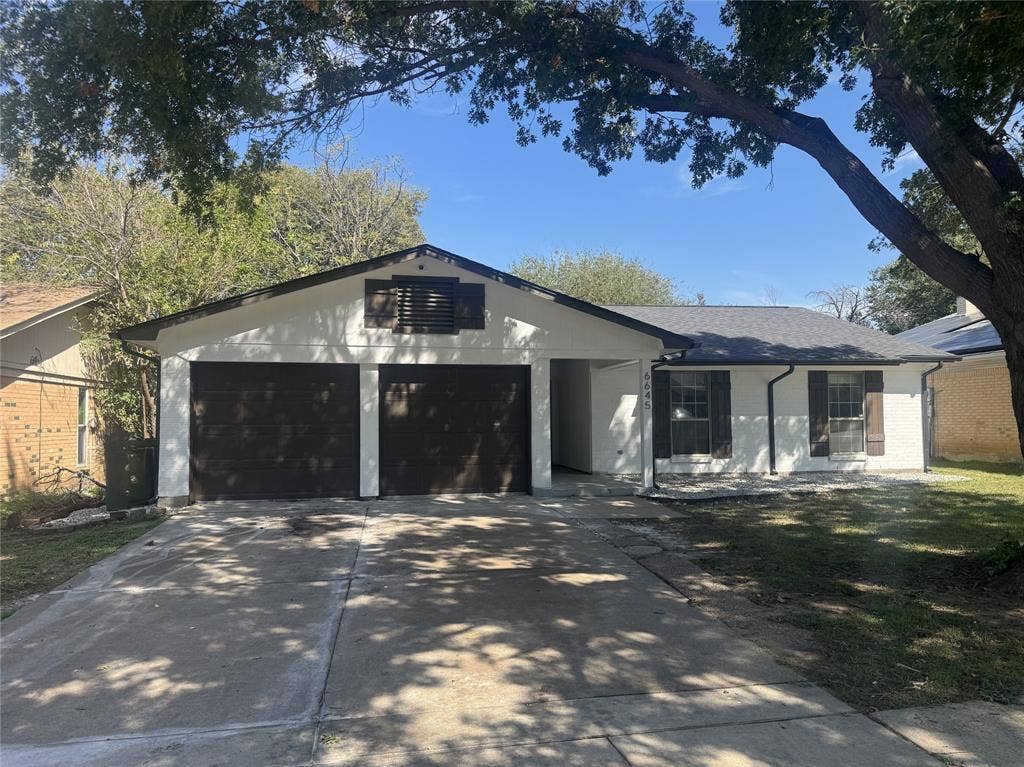 White exterior with dark trim and shutters, two-car garage, and a gabled roof