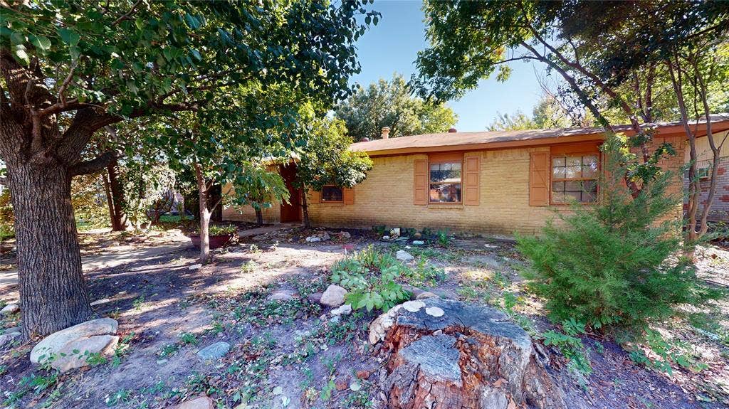 3214 Kenwood Drive, Rowlett, TX 75089 Single-story brick exterior featuring wooden shutters, a hipped roofline, and mature trees
