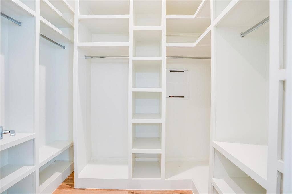 1612 Bennett Avenue, #105, Dallas, TX 75206 Walk-in closet featuring built-in white shelving, multiple hanging rods, and wood-finish flooring