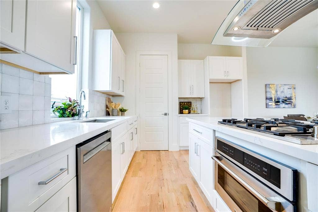 1612 Bennett Avenue, #105, Dallas, TX 75206 Modern kitchen featuring white cabinetry, light countertops, wood-finish flooring, a stainless steel dishwasher, and a built-in oven with a gas cooktop