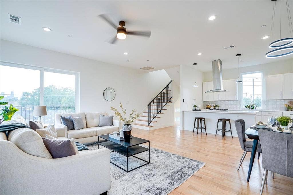 1612 Bennett Avenue, #105, Dallas, TX 75206 Open-concept living space featuring wood-finish flooring, a modern kitchen with a large island and stainless steel range hood, and a staircase with wrought iron balusters