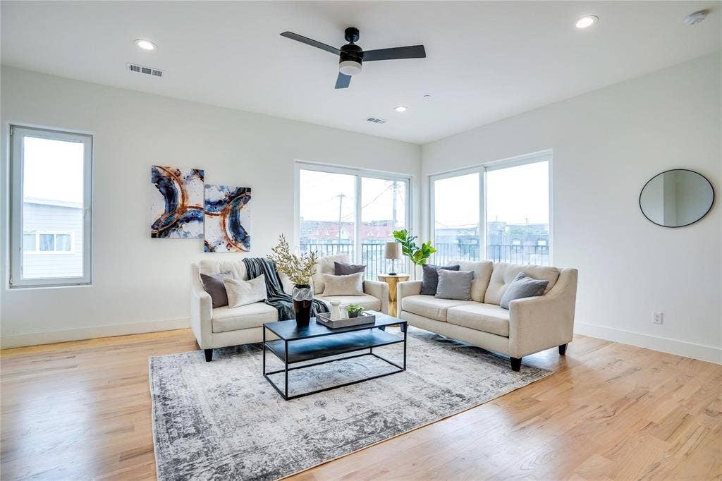 1612 Bennett Avenue, #105, Dallas, TX 75206 Spacious living area featuring light wood-finish flooring, white walls, and abundant natural light from multiple windows