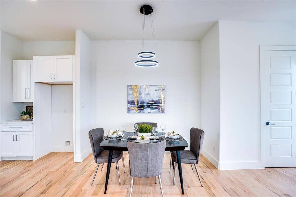 1612 Bennett Avenue, #105, Dallas, TX 75206 Bright dining area featuring wood-finish flooring, a modern chandelier, and a five-panel interior door with matte black hardware