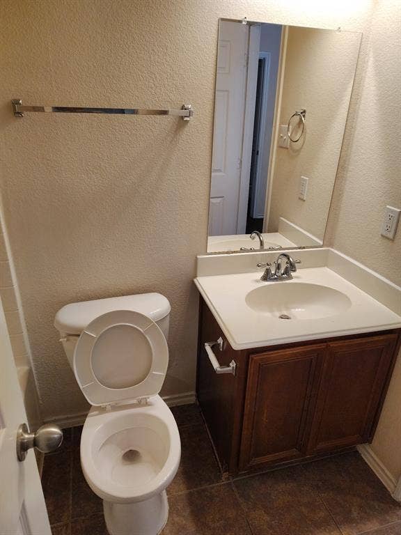 Vanity with wood-finish cabinetry, integrated sink, and laminate countertop