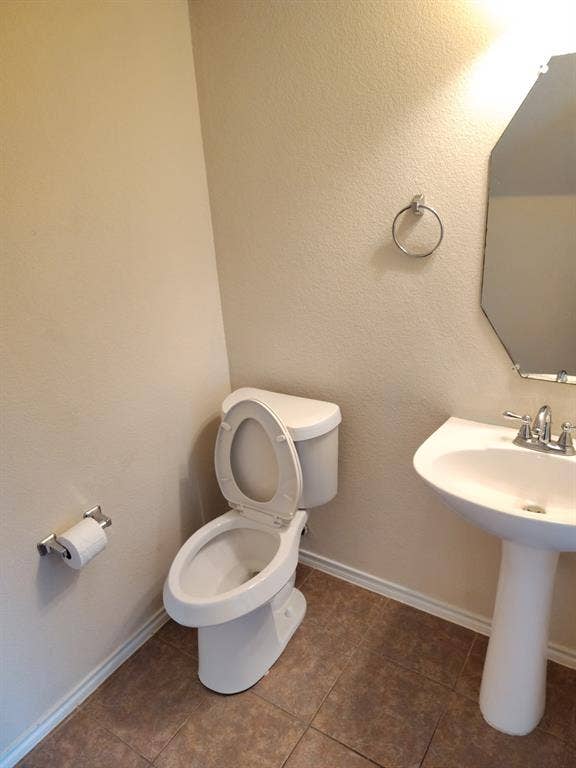 Pedestal sink with chrome fixtures, octagonal mirror, and tile flooring