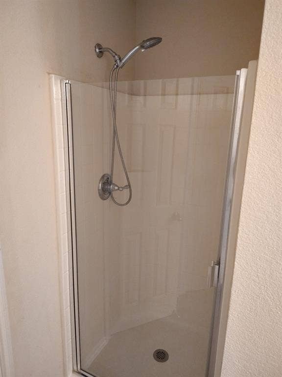 Shower enclosure with clear glass door, chrome fixtures, and built-in bench seating