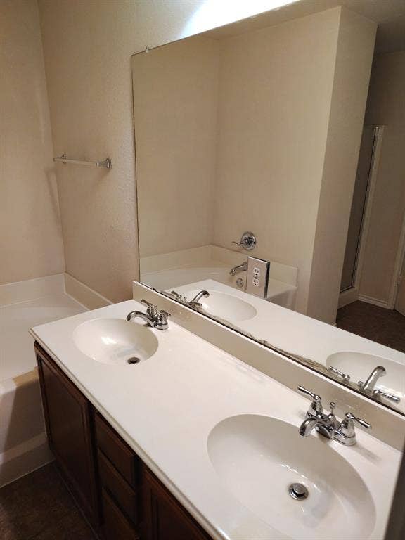 Dual vanity with integrated sinks, chrome fixtures, dark wood-finish cabinetry, and a large wall-mounted mirror