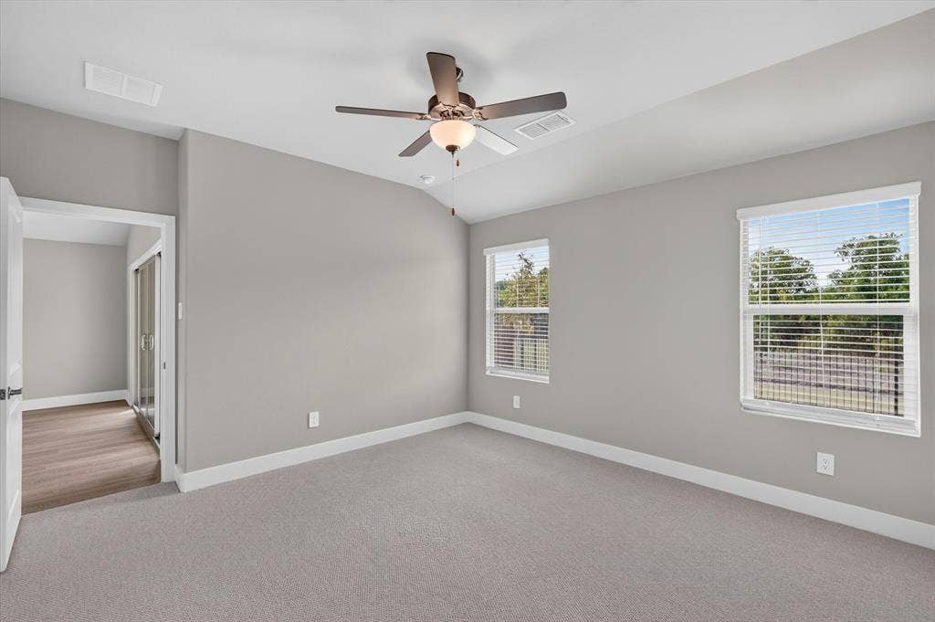 6108 Chickney Drive, Princeton, TX 75071 Neutral-toned room featuring a vaulted ceiling, ceiling fan with integrated lighting, wall-to-wall carpeting, and double-pane windows with horizontal blinds