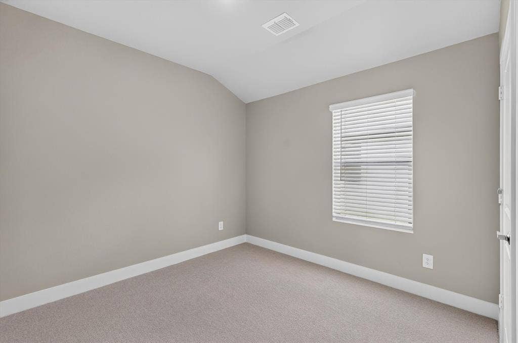 6108 Chickney Drive, Princeton, TX 75071 Neutral-toned interior space featuring wall-to-wall carpeting, a single window with horizontal blinds, and a slanted ceiling