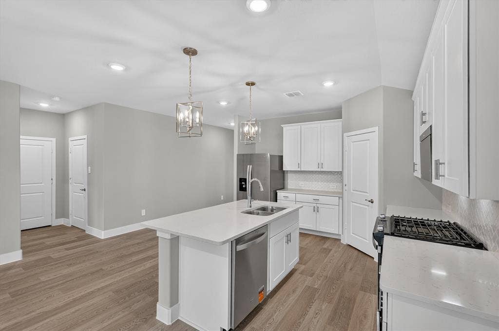 6108 Chickney Drive, Princeton, TX 75071 Kitchen featuring white shaker-style cabinetry, quartz countertops, stainless steel appliances, dual pendant lighting, and wood-finish flooring