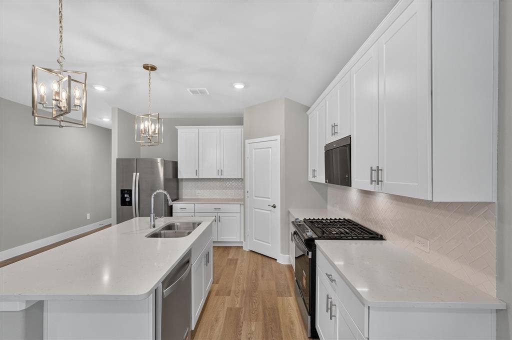 6108 Chickney Drive, Princeton, TX 75071 Kitchen featuring white shaker-style cabinetry, quartz countertops, herringbone-patterned tile backsplash, wood-finish flooring, and two brushed metal pendant lights