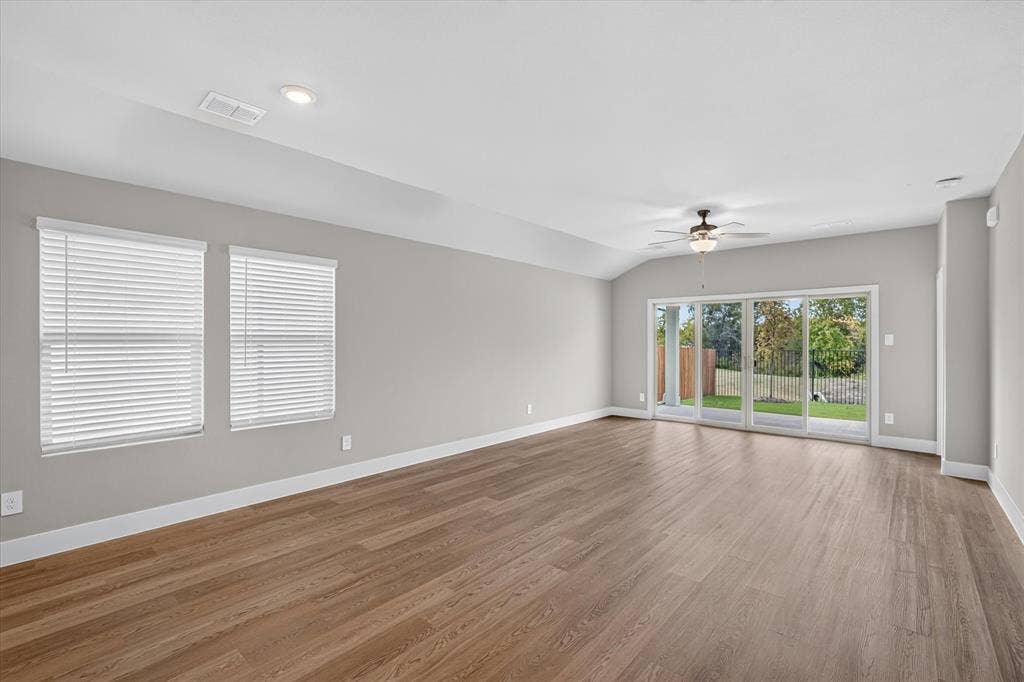 6108 Chickney Drive, Princeton, TX 75071 Spacious room featuring vaulted ceilings, wood-finish flooring, recessed lighting, a ceiling fan, and multi-panel sliding glass doors