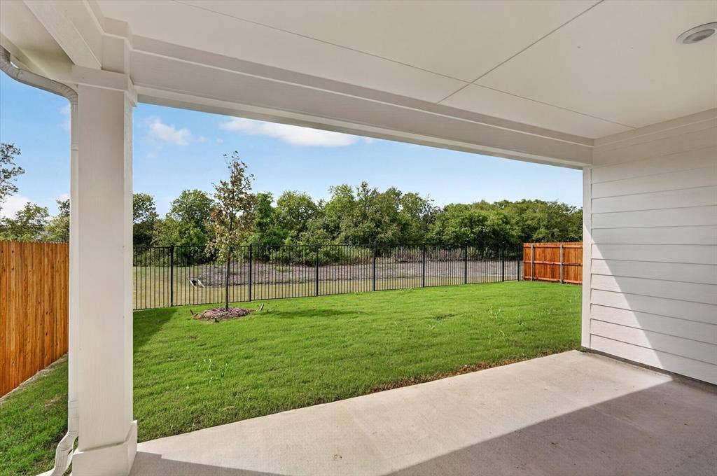 6108 Chickney Drive, Princeton, TX 75071 Covered concrete patio featuring white siding, a support column, recessed lighting, a fenced backyard with a lawn, and mature trees