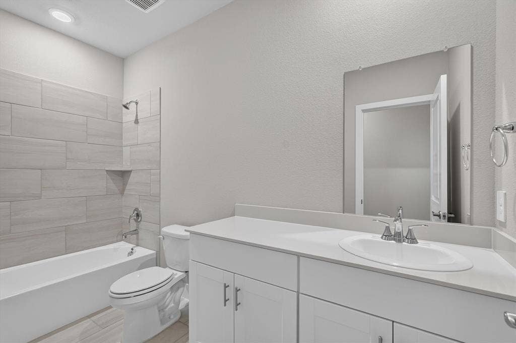 6108 Chickney Drive, Princeton, TX 75071 Bathroom featuring a white vanity with a solid-surface countertop, an oval undermount sink, recessed lighting, and a bathtub with large-format horizontal tile surround