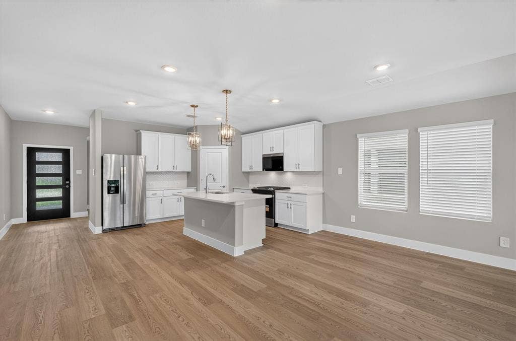 6108 Chickney Drive, Princeton, TX 75071 Kitchen featuring white cabinetry, wood-finish flooring, a center island with a built-in sink, stainless steel appliances, and recessed lighting