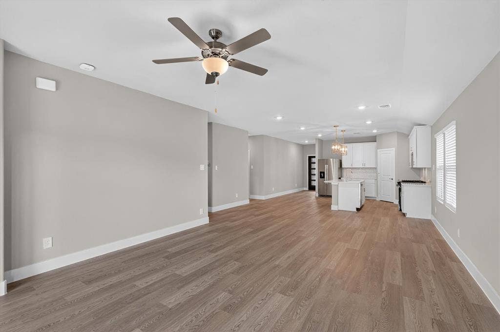 6108 Chickney Drive, Princeton, TX 75071 Open floor plan featuring wood-finish flooring, recessed lighting, ceiling fan, and kitchen with white cabinetry and a center island