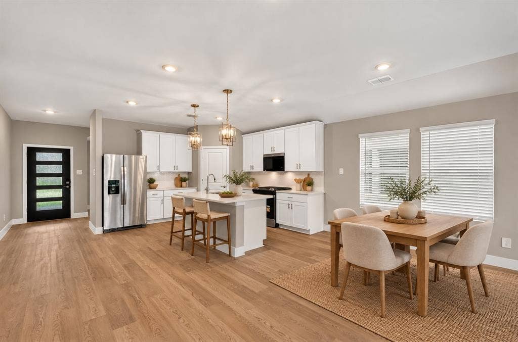 6108 Chickney Drive, Princeton, TX 75071 Kitchen featuring white cabinetry, wood-finish flooring, a central island with quartz countertops, stainless steel appliances, and pendant lighting