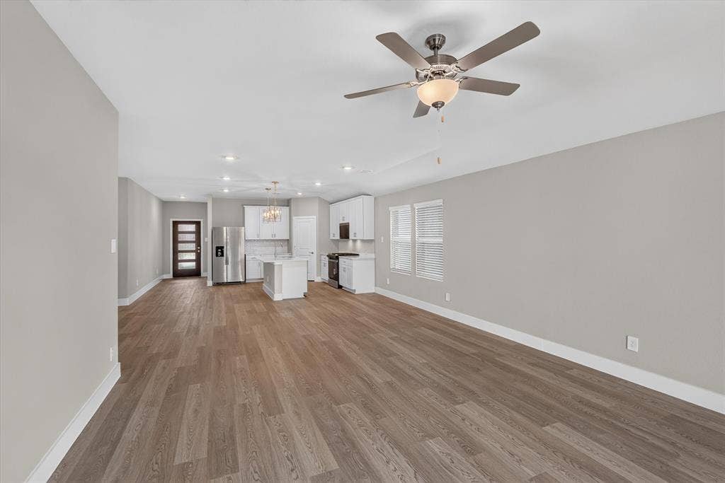 6108 Chickney Drive, Princeton, TX 75071 Open-concept area featuring wood-finish flooring, white cabinetry, a center island, stainless steel appliances, and a central ceiling fan with an integrated light fixture