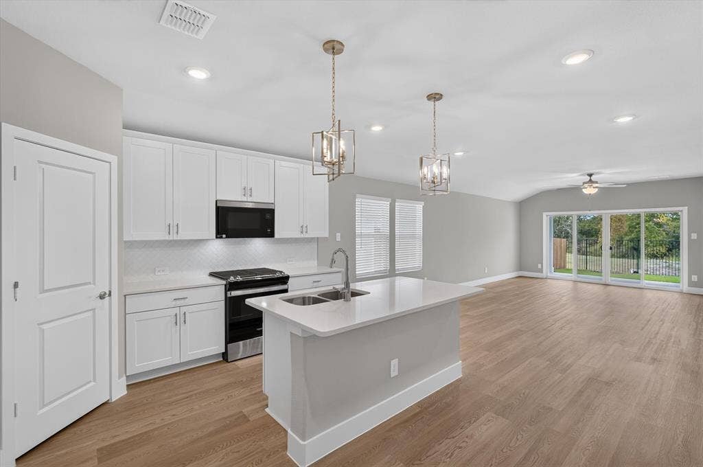 6108 Chickney Drive, Princeton, TX 75071 Kitchen featuring white cabinetry, quartz countertops, wood-finish flooring, a central island with an undermount sink, and metallic pendant lighting