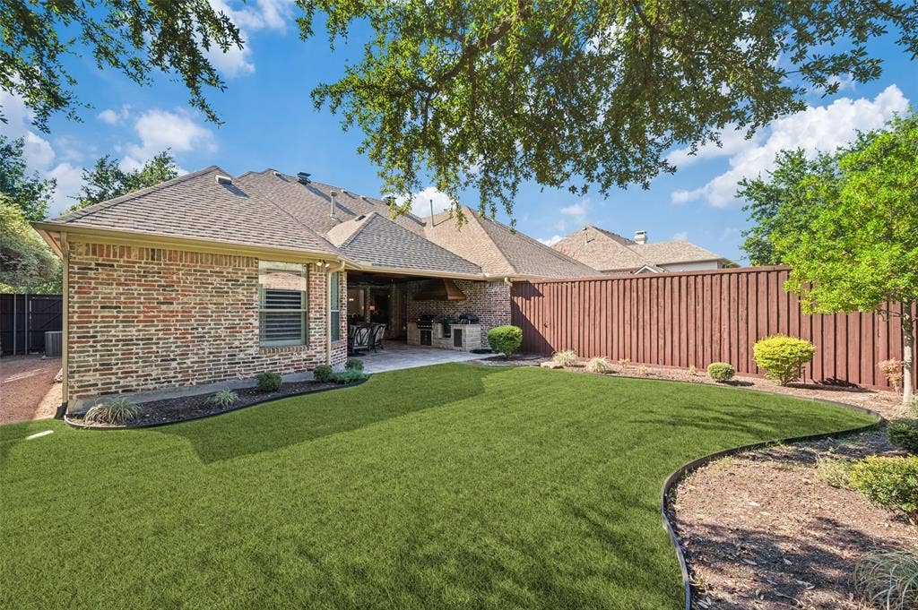 6168 Sweeney Trail, Frisco, TX 75034 Expansive backyard featuring a manicured lawn, an extended patio, and a privacy fence