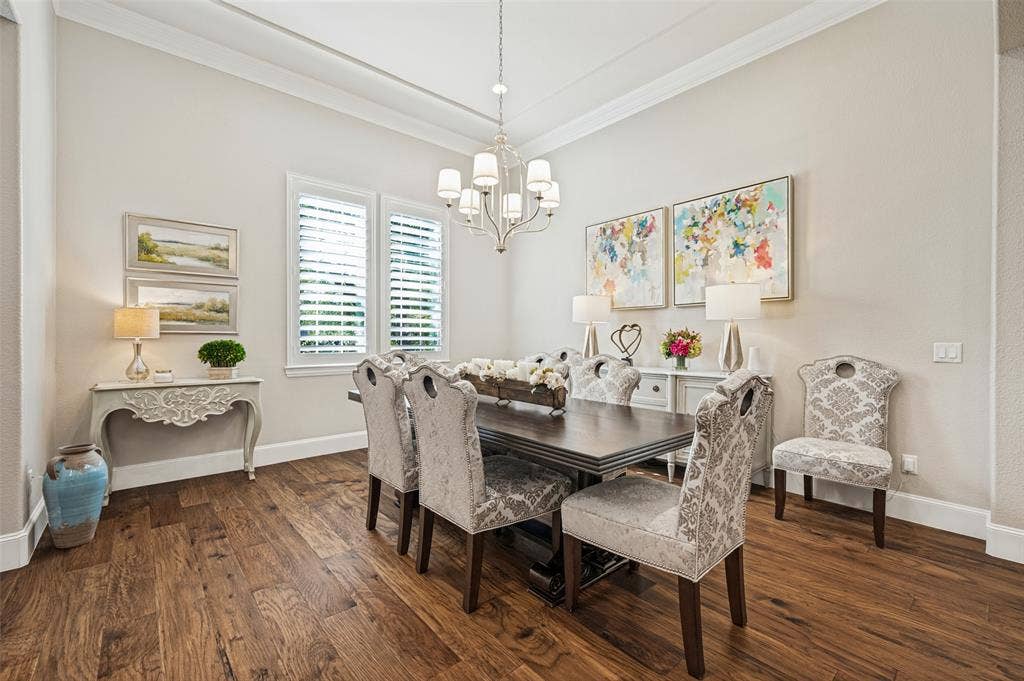 6168 Sweeney Trail, Frisco, TX 75034 Hardwood flooring, crown molding, white plantation shutters, and a classic chandelier