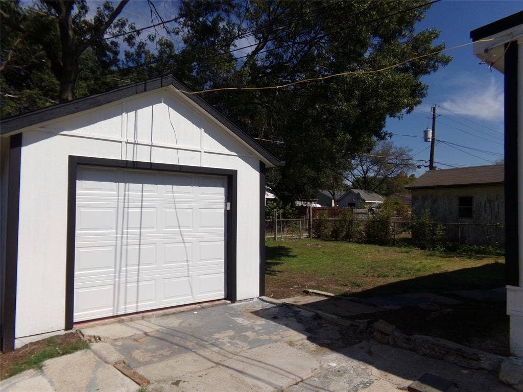 3423 Texas Drive, Dallas, TX 75211 Detached garage with a white paneled door, black trim, and a gabled roof