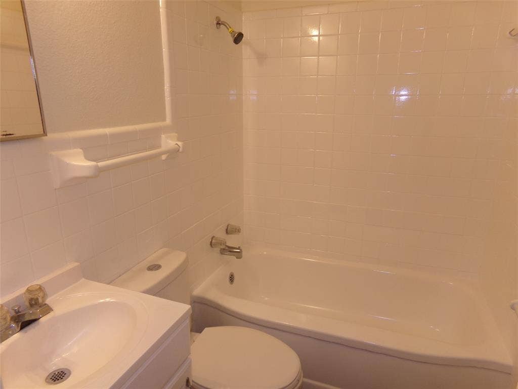 3423 Texas Drive, Dallas, TX 75211 White tile shower surround, integrated bathtub, and vanity with basin sink