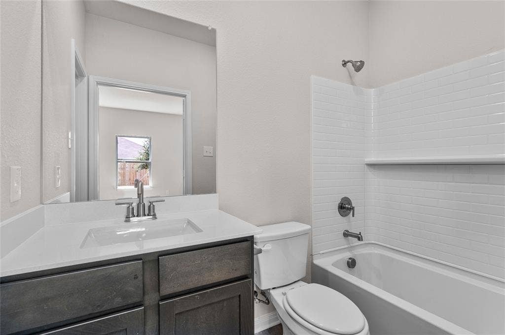 Full bath with  shower combination, vanity, and a textured wall