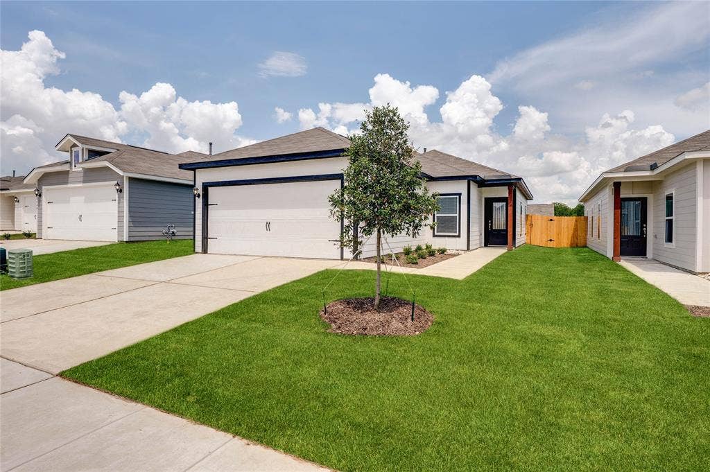 Ranch-style home featuring a garage, driveway, a shingled roof, and a gate