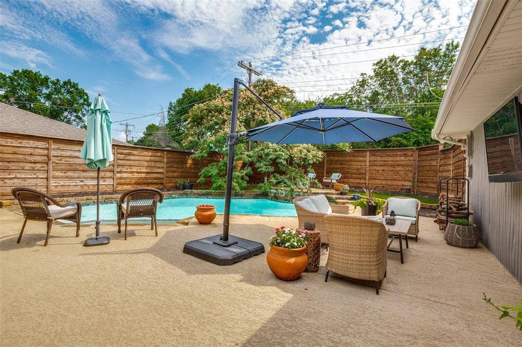 9421 Meadowknoll Drive, Dallas, TX 75243 Expansive concrete patio surrounding a swimming pool, bordered by a horizontal plank privacy fence