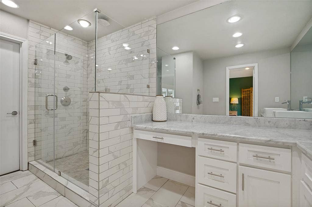 9421 Meadowknoll Drive, Dallas, TX 75243 Shower featuring clear glass enclosure, subway tile surround, rain showerhead, and wall-mounted shower system