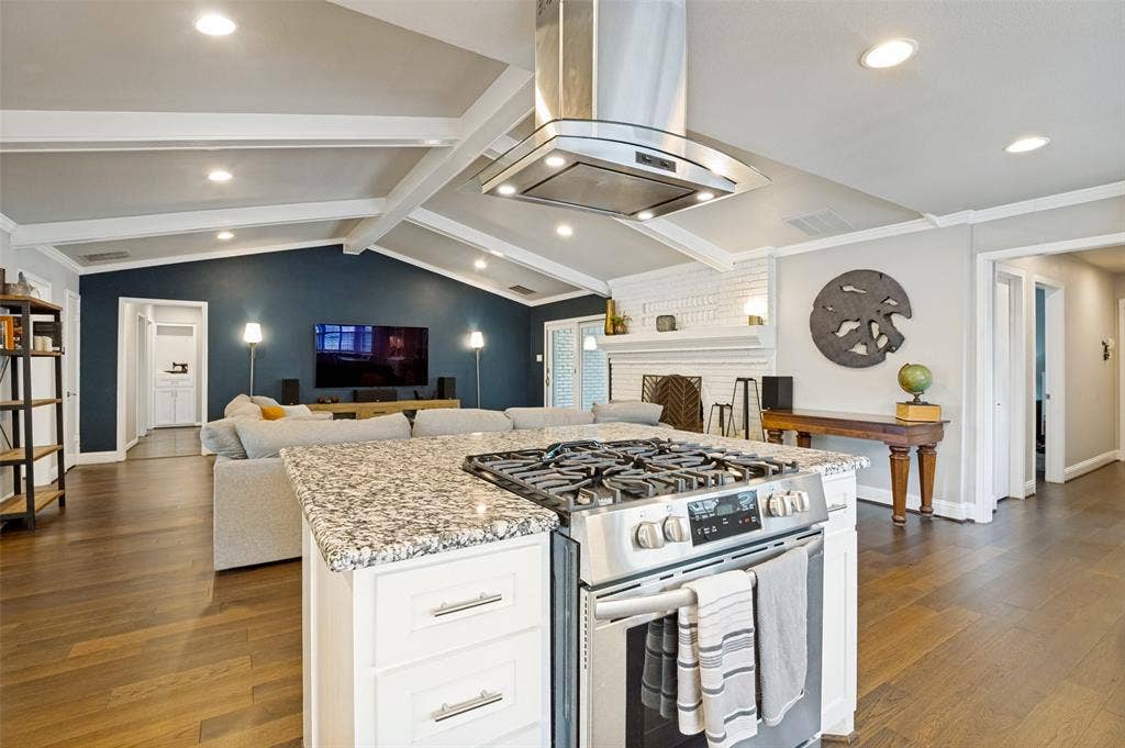 9421 Meadowknoll Drive, Dallas, TX 75243 Kitchen island featuring a built-in stainless steel gas range with a matching range hood and granite countertop