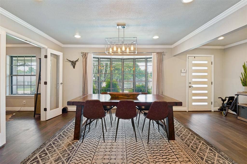 9421 Meadowknoll Drive, Dallas, TX 75243 Dining area featuring dark wood-finish flooring, a prominent bay window, and a modern chandelier