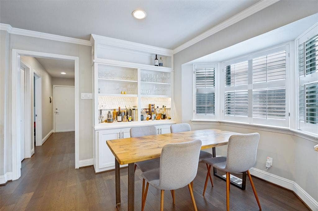 9421 Meadowknoll Drive, Dallas, TX 75243 Built-in cabinetry with glass shelving and illuminated backsplash, wood-finish flooring, recessed lighting, crown molding, and a bay window featuring plantation shutters