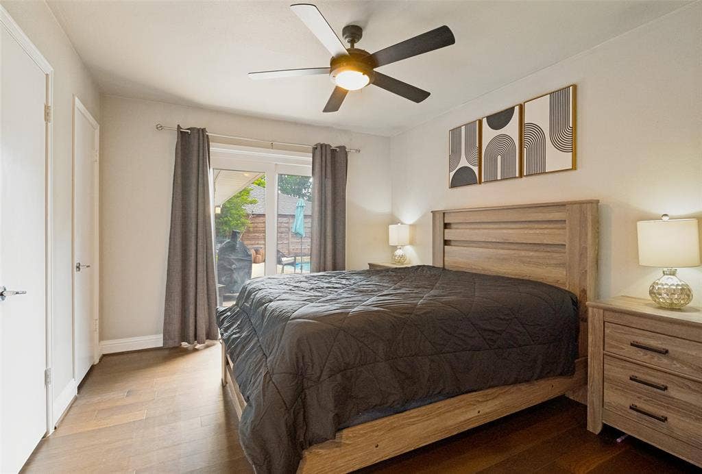 9421 Meadowknoll Drive, Dallas, TX 75243 Spacious bedroom featuring wood-finish flooring, a contemporary ceiling fan with integrated lighting, and a private patio entrance