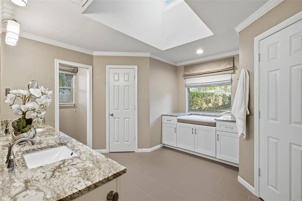 Spa-inspired primary bath with skylight, granite counters and a built-in window-seat nook.