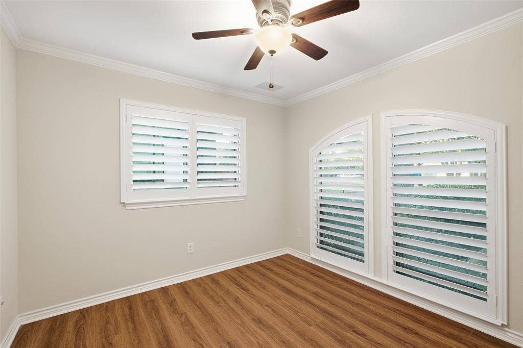 Flexible bedroom or home office with wood-look floors, plantation shutters and ceiling fan.
